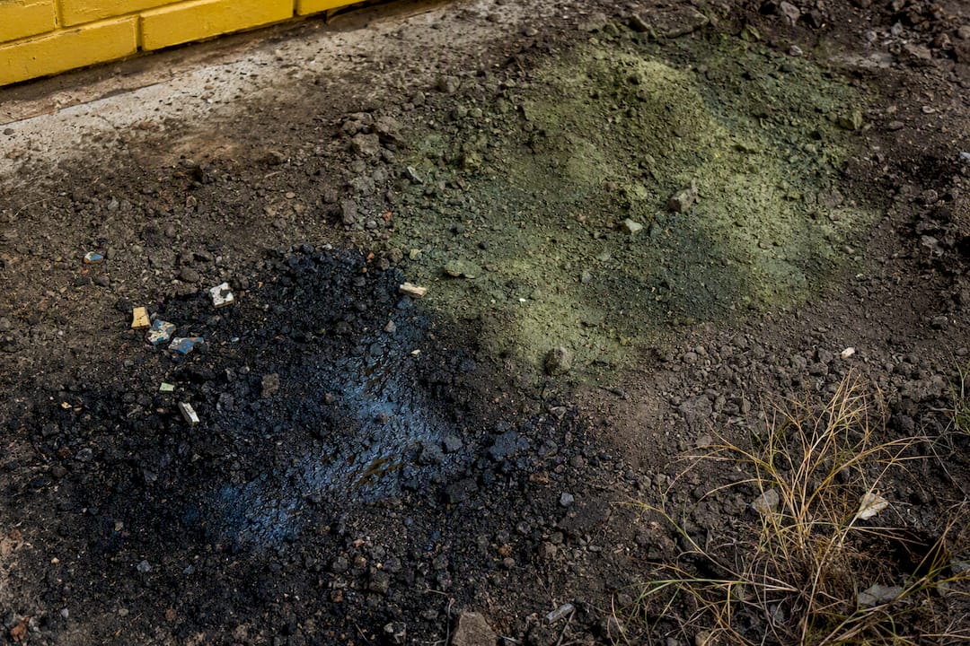 Unusual soil patches with oily sheen and debris