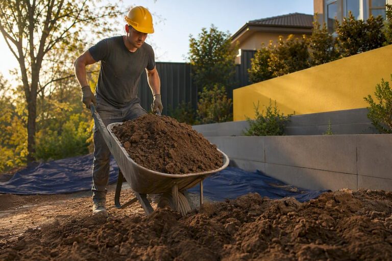 Worker moving excavated soil beside retaining wall
